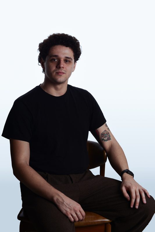 Retrato de Carlos sentado em uma cadeira de madeira, fundo claro